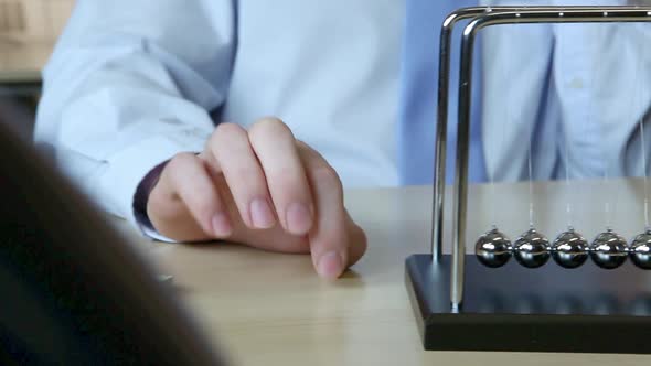 Person playing with newtons cradle