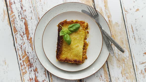 Homemade Tasty Meat Lasagna with Fresh Basil and Parmesan Cheese in a Plate on Wooden Background