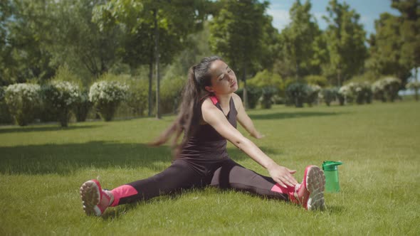 Asian Woman Training Muscles Sitting on Park Lawn