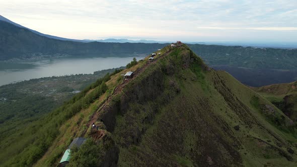 aerial over Mount Batur volcano with tourists standing on a ridge in Bali Indonesia