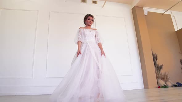 A Girl in a White Wedding Dress Poses Rotates the Hem
