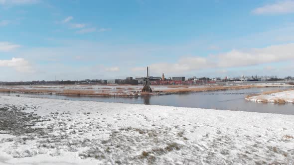 Snowy winter Dutch windmill polder land near highway, aerial view