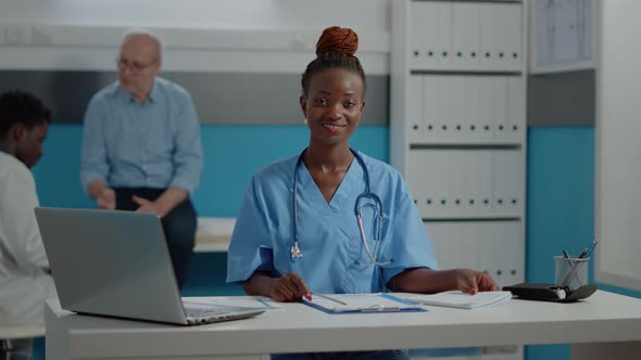 Young Adult Nurse Sitting at Desk with Laptop
