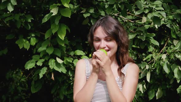 Attractive Young Woman Eating a Green Apple on a Background of Wood. Healthy Food. Fresh Fruits