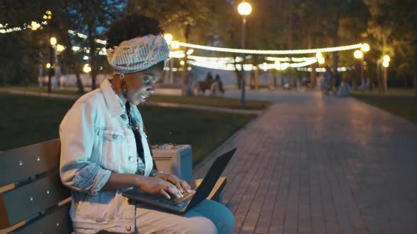 Afro-American Woman Using Laptop in Park in Evening