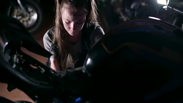 Young woman repairing her motorcycle in the garage