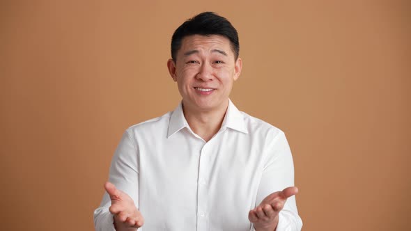 Pleased Asian businessman talking at the camera