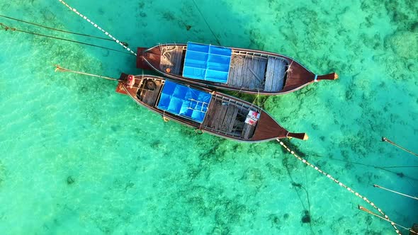 A zooming in shot of a Thai Long Tail boat while boat are dock from above with no people in the boat