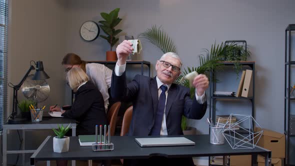 Elderly Man Boss Celebrating Business Success Dancing with Money Dollar Cash in Modern Office Room