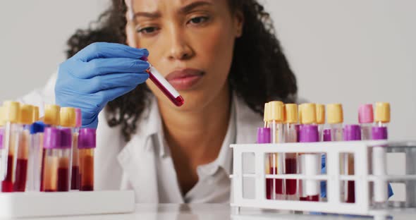 Video of biracial female doctor holding test tube on blue background