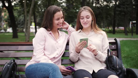Two Young Girls Students Using Mobile Phones While Outdoors