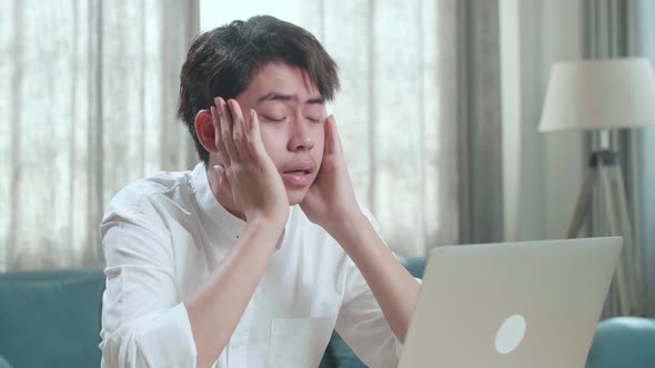 Close Up Of Asian Man Student Being Tired While Typing On Computer At Home