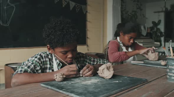 Siblings Shaping Clay on Lesson