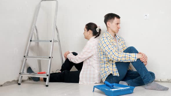 Depressed Woman and Guy Sit Near White Wall of New Apartment