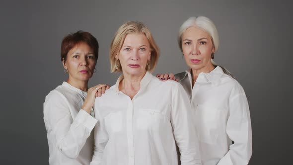 Studio Portrait of Three Adult Women in White Shirts Looking at Camera