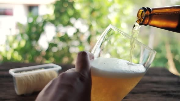 Slow Motion of Young Person Pouring Beer from Bottle into a Glass