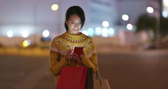 Woman Hold with Shopping Bag and Use of Mobile Phone in City 