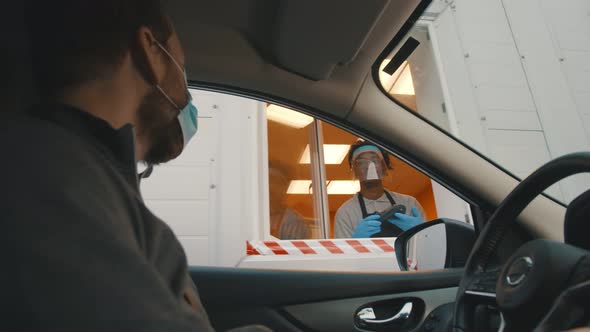 Man Driver in Mask Paying with Smartphone App in Drive Through Window