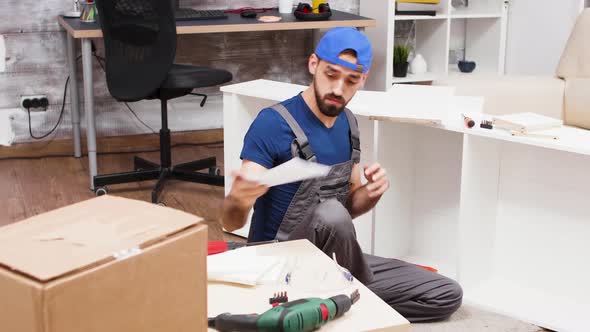 Male Worker in Coverall Sitting on the Floor Following Instruction