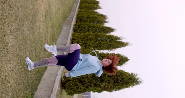 curly red-haired girl goes in for sports in nature not against the background of green tui