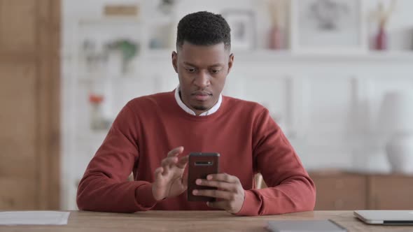 Attractive Young African Man using Smartphone in Office