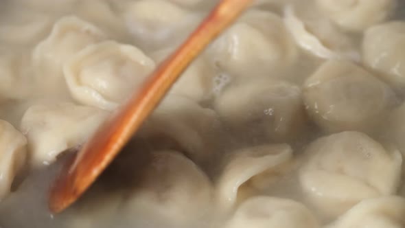 cooking dumplings. stir the dumplings with a wooden spoon