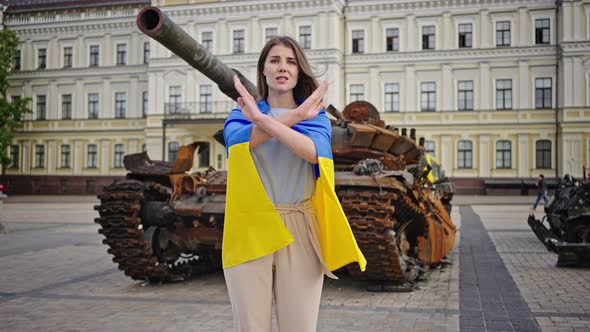 Ukrainian Woman Crosses Hands Showing Stop Gesture at Tank