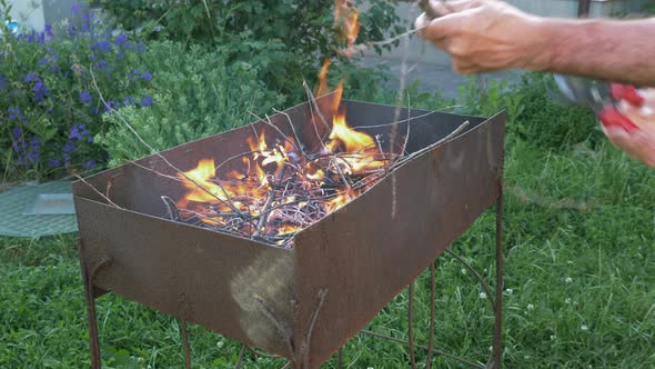 Man making fire flames for preparing grill. Flames from trees for grill or BBQ. Charcoal on fire