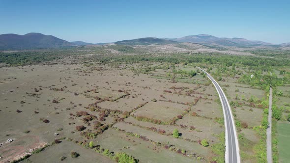 Aerial View Empty Asphalt Road on the Plateau Between Green Fields Highland Way