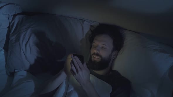 Gadget Night Relaxed Man Scrolling Phone in Bed