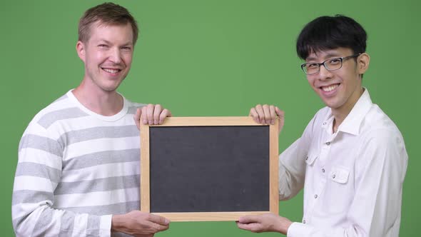 Two Happy Young Multi-ethnic Businessmen Holding Blackboard Together