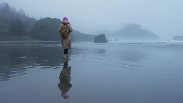 Aerial Drone Shot Smiling Woman Spinning on Wet Beach with Scenic Reflection