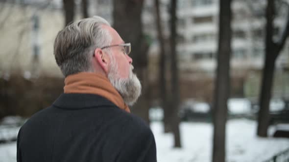 Medium shot of a respectable man with glasses walking in the park