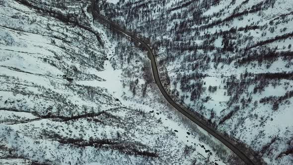 Flying over country road in snowy valley.