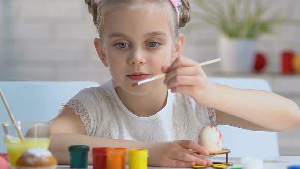 Diligent Girl Carefully Putting Pattern With Paints on Egg, Easter Decoration