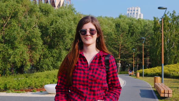 A Woman in Red Plaid Shirt and Sunglasses in the Sunny Park