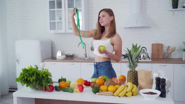 Sporty woman standing near fruits. Happy young woman with muscular body standing in the kitchen