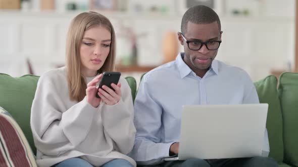 Woman Using Smartphone While Man Using Laptop at Home Couple