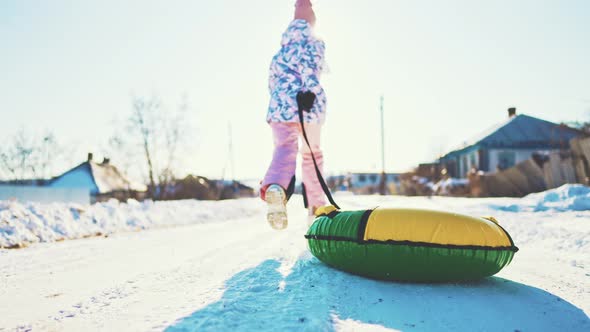 Funny Child Sliding on Snow Tubing on Slope Outdoors in Winter