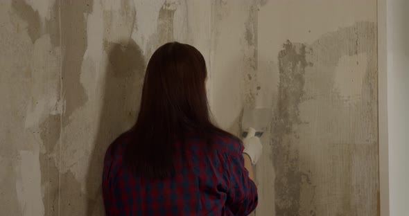 Close Up of Female in Gloves with Spatula Flattens Wall in Room