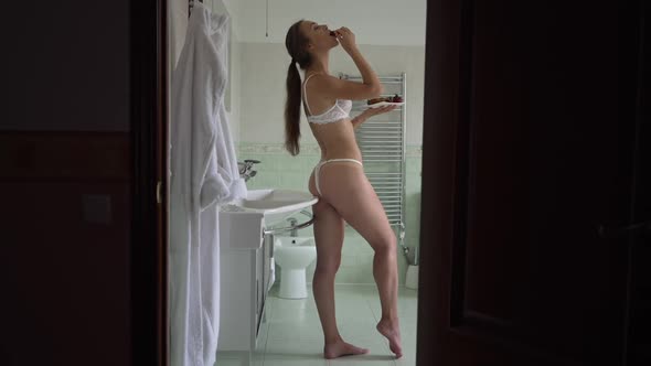 Wide Shot Seductive Slim Woman Eating Strawberry in Slow Motion Standing in Bathroom Indoors