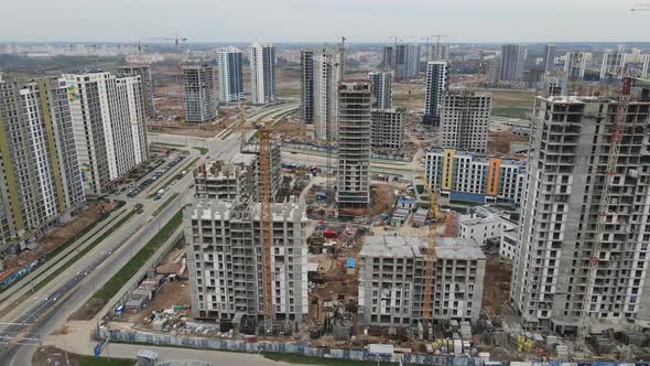 Flight Over The Construction Site. High Rise Buildings Under Construction And Construction Cranes