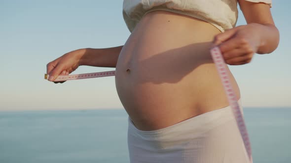 Young Female Measuring How Big Her During Pregnancy Belly Still Is.