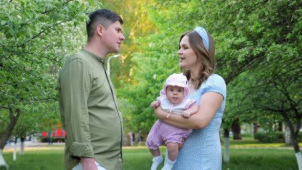 Long Haired Blonde Holding Baby Girl Talks to Husband