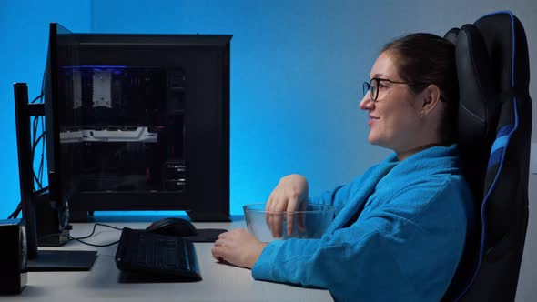 Young Woman Watches Stream with Computer and Eats Popcorn