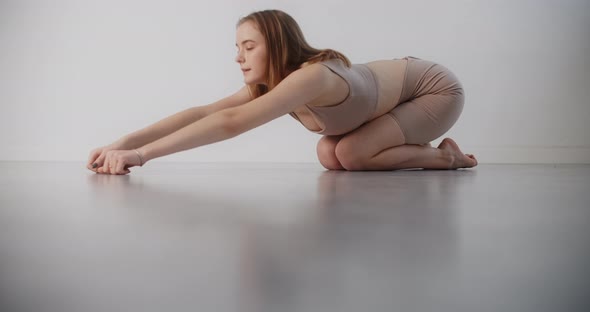 Yoga Instructor Does Exercises on the Floor in Slow Motion Young Woman in Beige Costume Does Pilates