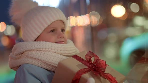 Portrait Boy with Gifts Box Looking and Dreaming in Christmas Window Shopping on Traditional