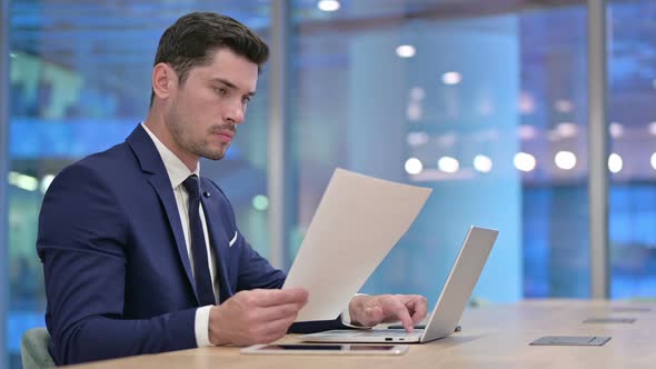 Businessman Working on Laptop and Documents at Work