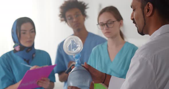 Indian Doctor Showing Breathing Bag to Group of Diverse Interns