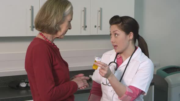 CU TU Female doctor giving pill bottle to senior patient in hospital / London, United Kingdom